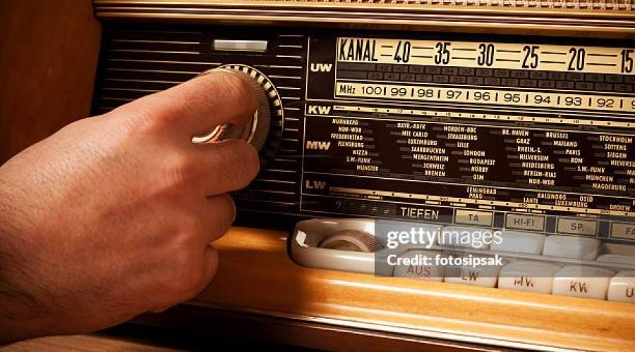 man turning volume control button of a old fashioned radio