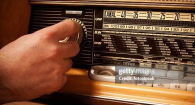 man turning volume control button of a old fashioned radio