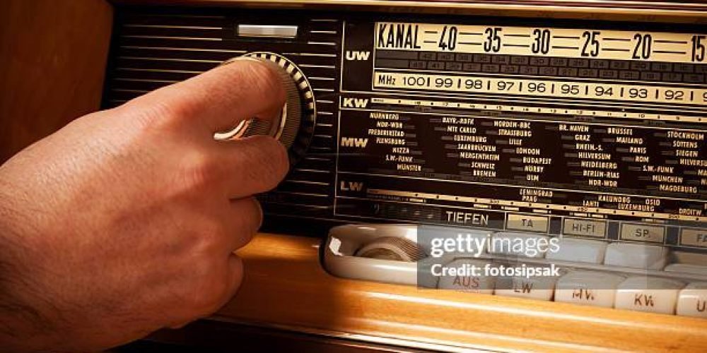 man turning volume control button of a old fashioned radio