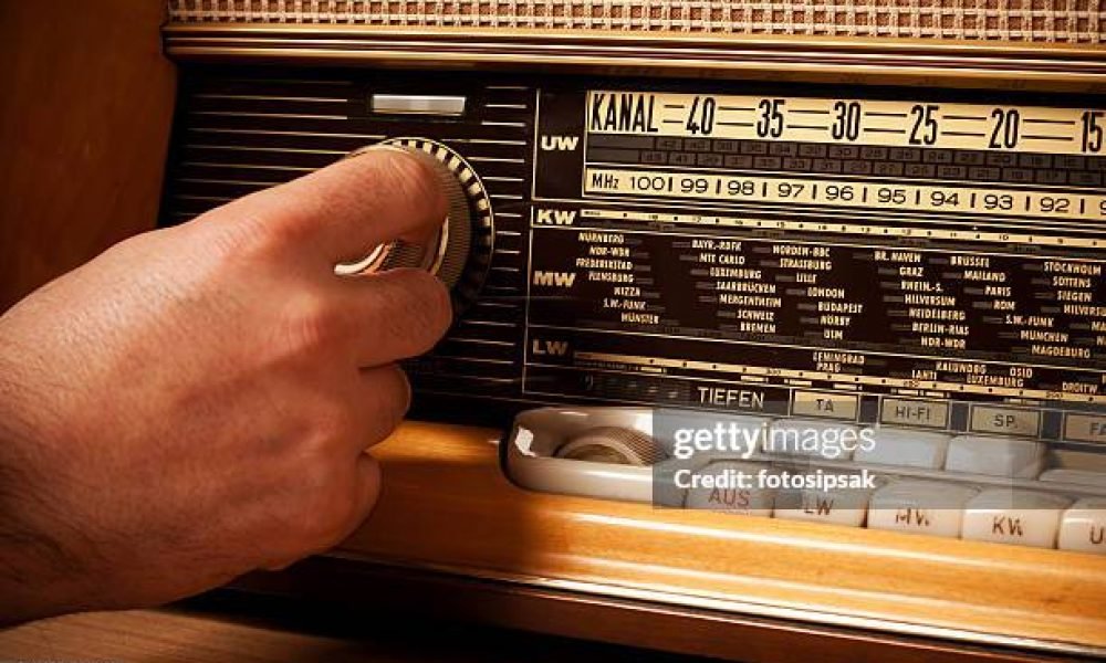 man turning volume control button of a old fashioned radio